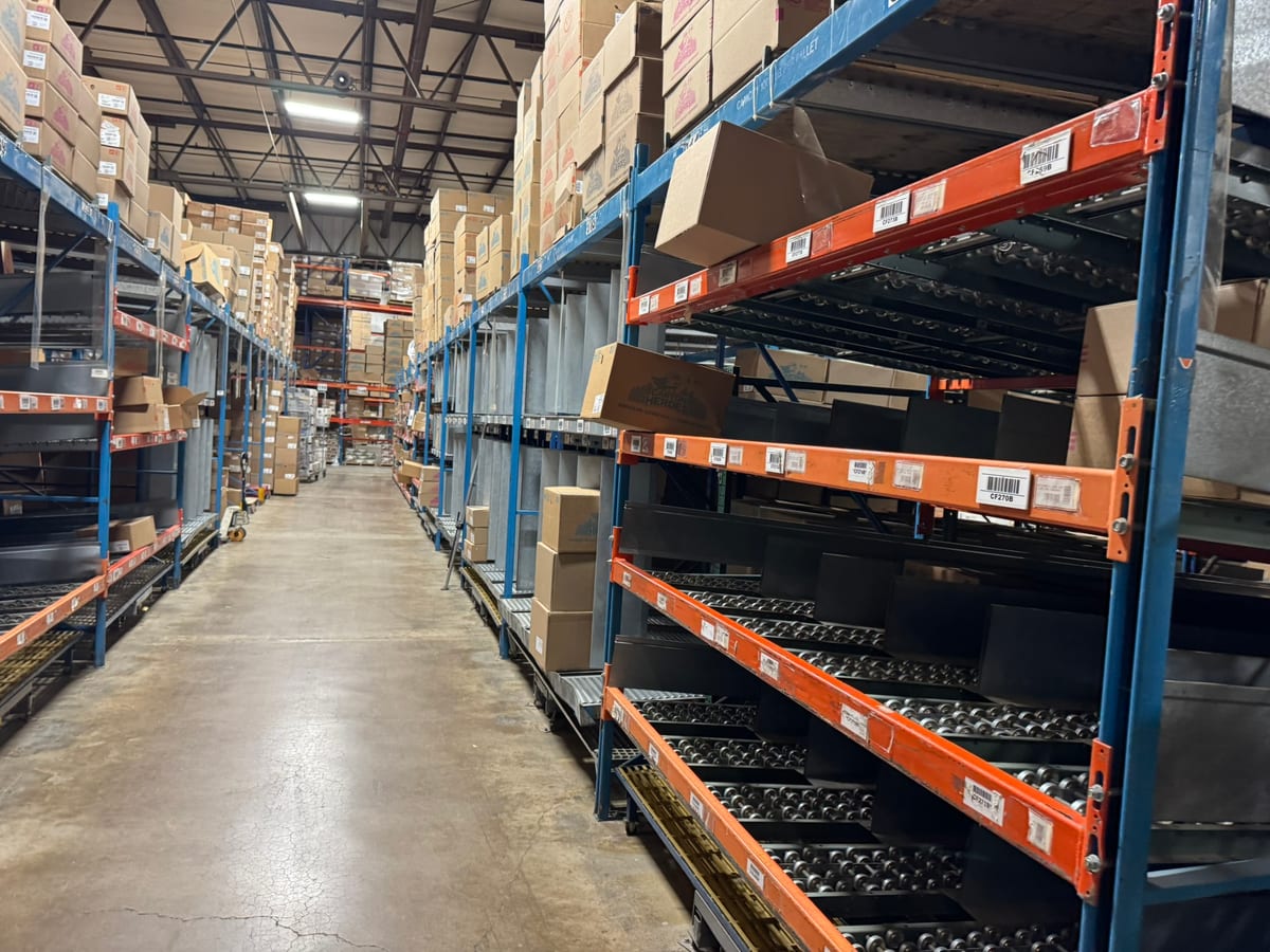 Stocked carton flow rack aisle with roller tracks and cased product in a beverage pick module